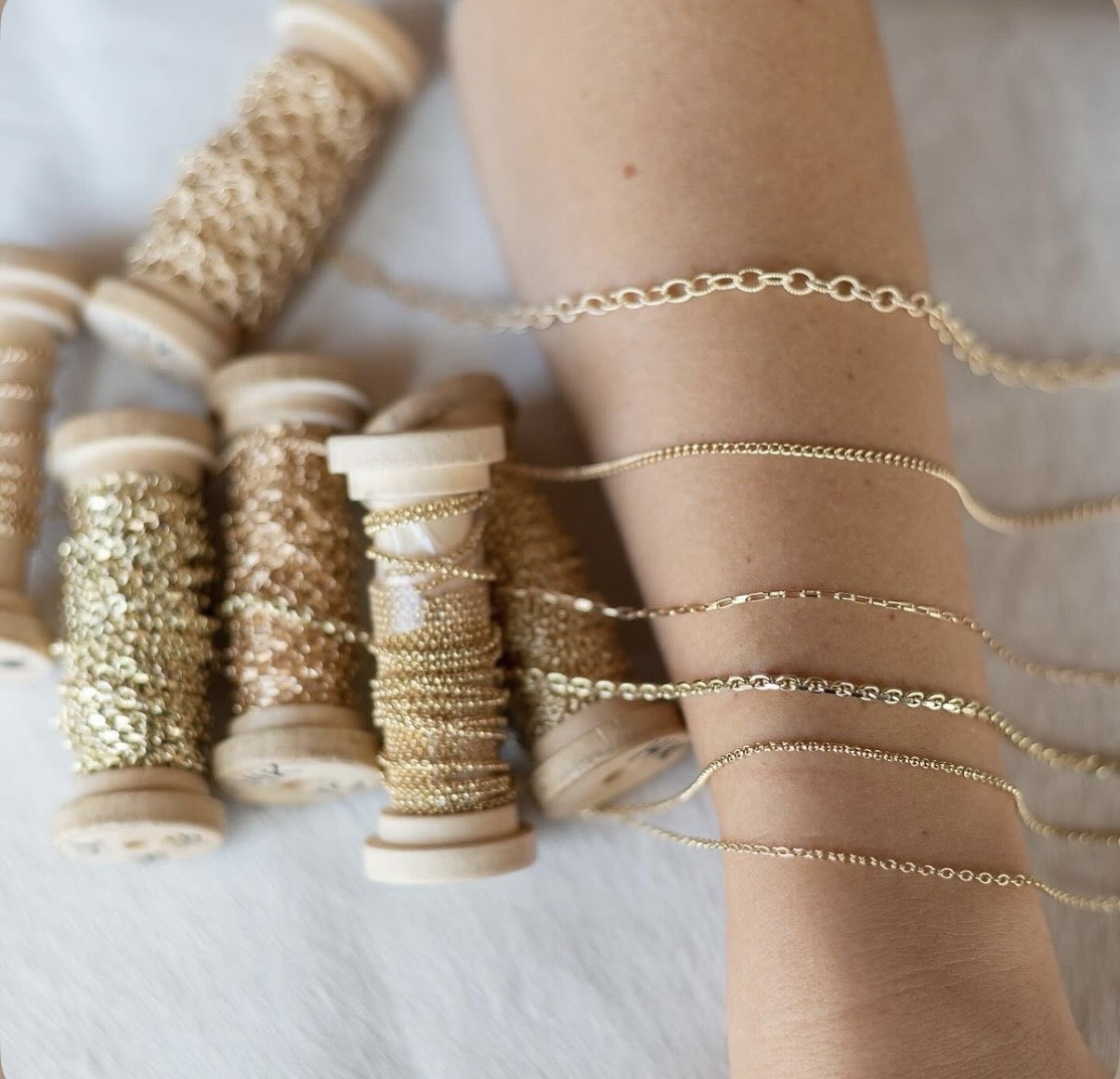 Several delicate gold chains draped over a wrist